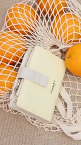 Billetera color amarillo pastel con cierre de cremallera y presilla con broche. Incluye espacio para tarjetas, billetes y monedero con cierre.