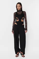 Body negro de microtul y encaje con aberturas en el torso, mangas largas con mitones y cuello alto doble con encaje.
