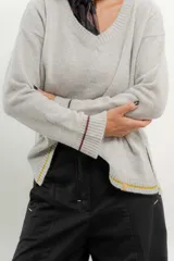 Sweater de punto gris con cuello en V y ribetes en contraste.