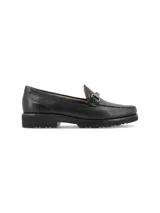Mocasín de cuero negro con detalle de hebilla metálica plateada.
