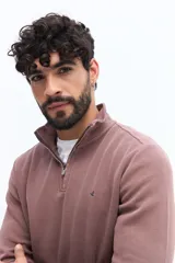 Buzo de algodón color verde musgo, con cuello alto y cierre frontal parcial. Presenta puños y cintura acanalados, y un pequeño logo bordado en el pecho.