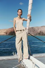 Pantalón de tiro alto color beige confeccionado con lino, de pierna recta, con bolsillos delanteros y falsos bolsillos de vivo en la espalda.