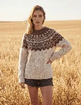 Buzo de lana merino tejido a mano en Uruguay, de color beige con diseño geométrico en tonos marrones alrededor del cuello y hombros. Presenta cuello redondo, mangas largas y terminaciones acanaladas en puños y ruedo.