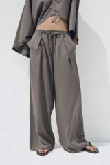 Pantalón blanco de lino, de corte ancho y tiro medio, con cintura elástica ajustable con cordones y bolsillos laterales.