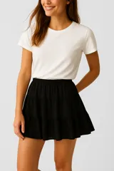 Minifalda negra de algodón con cintura elástica y diseño escalonado de tres volantes.
