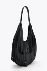 Bolso de hombro negro con flecos en el cuerpo, asa de hombro, bolsillo interior con cremallera y cierre mediante imán.