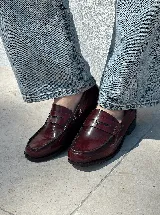 Mocasines de cuero color borgoña con detalle de aplique metálico plateado en el empeine.