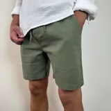 Bermuda color verde militar, de corte recto y largo a la rodilla, con cintura ajustable con cordón y bolsillos laterales. Confeccionada en simil lino.