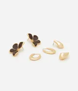 Set de tres pares de aros dorados: un par con forma de flor esmaltada en marrón, un par de aros tipo argolla y un par de aros con forma de gota.
