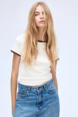 Remera blanca entallada de punto suave con cuello y mangas con ribete marrón.