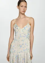 Vestido corto color crema con estampado floral en tonos azules y verdes, con escote en V, breteles finos y volados en el escote y ruedo. Presenta lentejuelas bordadas y cierre lateral invisible.