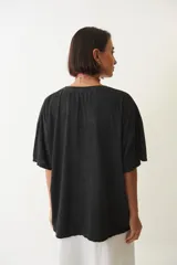 Remera negra de corte amplio con estampa de botas de cowboy rosas y flores.