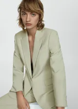 Blazer color verde claro, con cuello de pico con solapa y solapas con muesca. Tiene forro interior, manga larga con puños abotonados, dos bolsillos de solapa en la parte delantera y cierre delantero con botones.