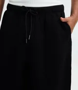 Pantalón baggy color beige, confeccionado en algodón con felpa. Presenta cintura elástica con cordón ajustable, bolsillos delanteros y un bolsillo trasero. El bajo es ajustable con elástico.