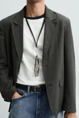 Blazer regular fit color gris oscuro confeccionada en tejido con estructura. Cuello con solapas de muesca y manga larga. Bolsillos de solapa en cadera. Cierre frontal de botonadura.