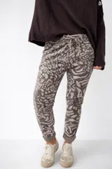 Pantalón de mujer con estampado animal print en tonos grises y marrones, con cintura elástica y cordón ajustable. El diseño es de corte recto y los puños están doblados.