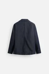 Blazer azul oscuro de denim, corte relaxed fit, con cuello de solapas de muesca, manga larga con puños abotonados, bolsillos de solapa en la cadera, abertura en el centro de la espalda y cierre frontal con botones. Sin forro interior.