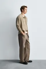 Cárdigan color beige de corte relaxed fit, tejido en hilatura con algodón y ramio. Tiene cuello redondo, manga larga, acabados en rib y cierre frontal de botonadura.