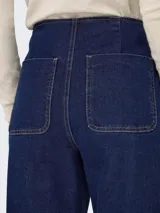Pantalón de jean azul oscuro, de corte ancho, tiro alto y cierre de botones.