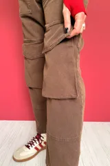 Pantalón cargo color marrón con cintura elástica ajustable con cordón, bolsillos laterales y bolsillos tipo parche con solapa en las piernas.