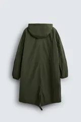 Parka verde militar de tejido técnico ligero, corte oversize, cuello alto con capucha ajustable, manga larga con puños elásticos, cintura ajustable con cordón interno, bolsillos con solapa, bajo asimétrico con abertura trasera ajustable y cierre frontal con cremallera oculta y botones a presión.