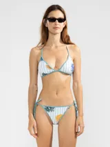 Conjunto de bikini reversible con estampado de rayas y flores. El corpiño es de triángulo con tirantes finos y la bombacha es de corte clásico con lazos laterales.
