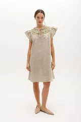 Vestido corto celeste de lino, corte suelto, con cuello redondo con volados y lazo, mangas cortas con volados.