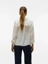 Camisa color crudo de corte recto, con cuello clásico, manga larga con puños abotonados, cierre frontal con botones y dos bolsillos de parche en el pecho.