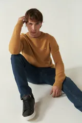 Sweater mostaza de punto con cuello redondo, mangas largas y logo bordado en el pecho. Corte slim fit.