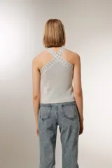 Top cropped gris metalizado con cuello halter y detalle de studs.