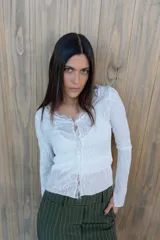 Remera de encaje blanca con mangas largas y broche metálico en el centro. Incluye musculosa de lycra blanca como forro.