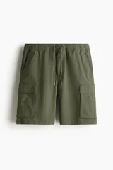 Short cargo color verde militar, de corte regular, con cintura elástica ajustable con cordón, bolsillos laterales, bolsillos cargo con solapa y cierre autoadherente en las piernas y bolsillos traseros con solapa y cierre autoadherente.