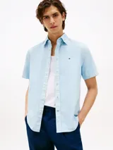 Camisa celeste de corte regular, confeccionada en algodón Oxford con cuello abotonado, manga corta y logo de Tommy Hilfiger bordado en el pecho.