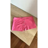 Shorts de cuero sintético color rosa con cierre lateral con tres botones plateados.