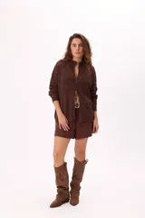 Cárdigan tejido calado color crudo con cierre frontal, cuello alto y mangas largas.