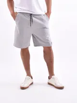 Bermuda deportiva gris melange con cintura elástica ajustable con cordón, bolsillos laterales y largo a la rodilla.