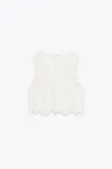 Top chaleco blanco de crochet con escote en pico y cierre frontal con lazos.