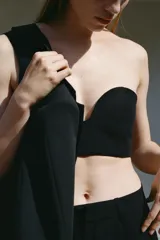 Top bandeau negro con escote corazón, hombros descubiertos y cierre trasero con ganchos metálicos.