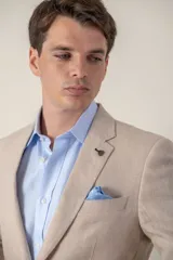 Saco de lino color beige, corte slim fit, con solapa de muesca, cierre de dos botones, bolsillo en el pecho y dos bolsillos delanteros con solapa. Medio forro.