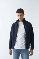 Campera tejida bondeada color verde musgo, con cuello alto, cierre frontal completo, bolsillos laterales con cierre y logo estampado en el pecho.