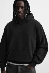Sudadera con capucha gris confeccionada en tejido de algodón con interior rizo. Tiene manga larga, bolsillo frontal tipo canguro y acabados en rib.
