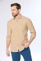 Camisa de lino color beige, de manga larga, con cuello clásico y bolsillo en el pecho.