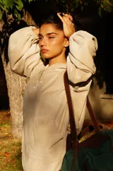 Buzo tipo canguro oversize de tela plush, color azul claro. Presenta capucha, cierre frontal parcial con cordón turquesa y bolsillos canguro frontales. Las mangas son largas y abullonadas con puños ajustados.