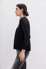 Sweater negro de poliéster, acrílico, poliamida y lana, con calce holgado, mangas largas y terminaciones en punto rib. Presenta bordado de lentejuelas y piedras con la frase "Tonight the night".