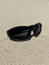 Gafas de sol negras con montura rectangular, lentes oscuras y detalle de estrella plateada en el lateral.