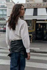 Camisa blanca de popelín con vivos negros a contraste en el cuello, el frente y los puños. Presenta un corte holgado y mangas largas con puños anchos.