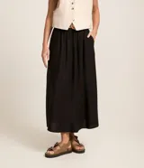 Pollera midi evasé color negro, confeccionada en viscolino, con trabillas en la cintura y cinturón de ráfia con hebilla redonda.