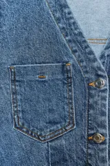 Vestido corto de denim azul, con cuello solapa, escote en pico, manga corta, bolsillos delanteros y cierre frontal con botones metálicos.
