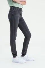Pantalón de jean negro gastado, tiro alto, corte ajustado en cadera y muslos, y pierna skinny.
