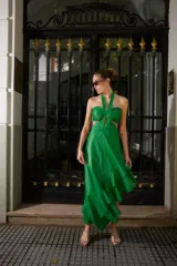 Vestido midi de cuero sintético color verde, con escote halter, cut-outs laterales y falda asimétrica con volados.